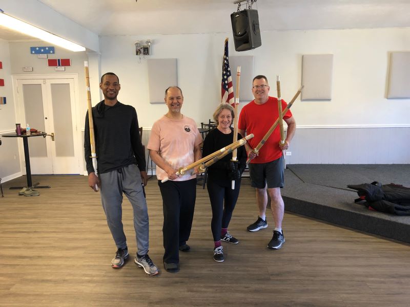 four people in the office posing with wooden swords